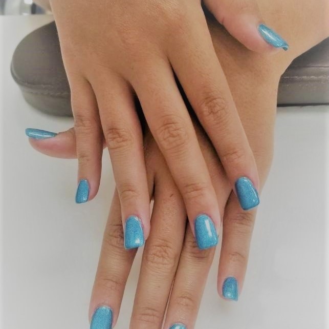 a square-tip manicure with a sparkling sky blue gel
						polish