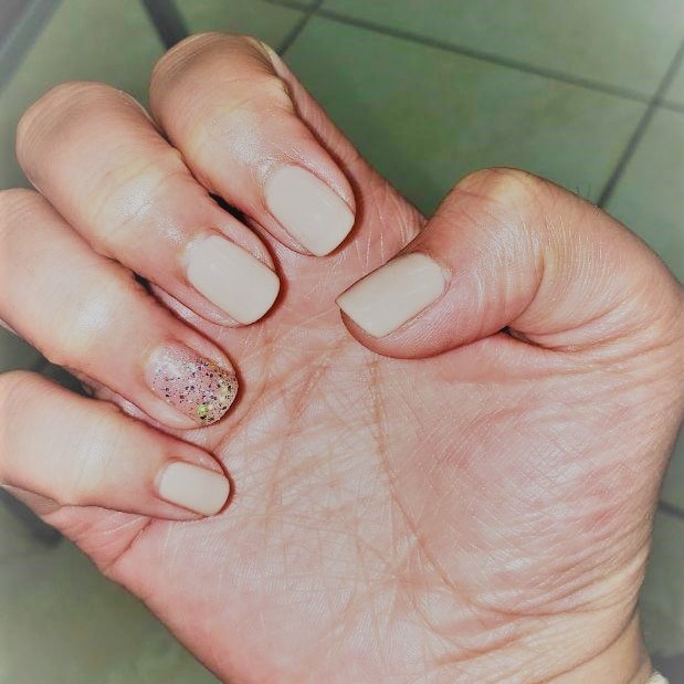 a classic nude gel manicure with a tasteful glitter ring
						finger